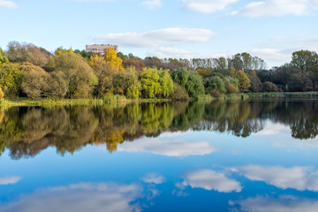 Fototapeta na wymiar Autumn trees on lake bank reflect in calm water. Moscow, Russia. 