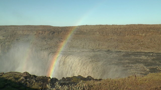 rainbow above detifoss waterfall in iceland visited by tourists