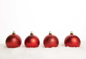 Red christmas ball ornaments lying on snow on a white background