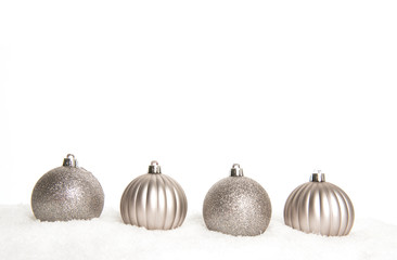 Silver christmas ball ornaments lying on snow on a white background