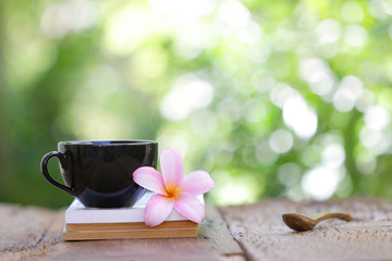 black coffee cup with flower and notebook on wooden table