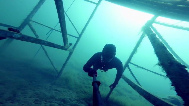 Freediver Exploring a Big Underwater Metalic Structure