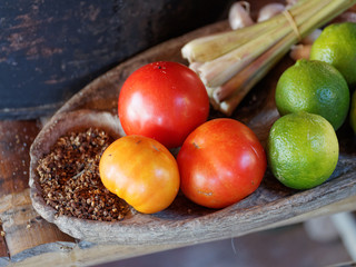 Thailand herb ingredients: lemongrass, lime, lemon, tomato, garlic and pepper on wood plate.
