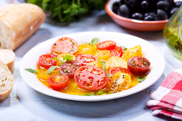 plate of colorful tomatoes with oil and basil