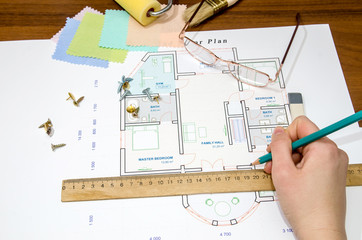Hand of designer drawing the apartment, view from above