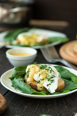 Poached egg on a piece of bread with spinach on the wooden table