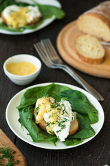 Poached egg on a piece of bread with spinach on the wooden table