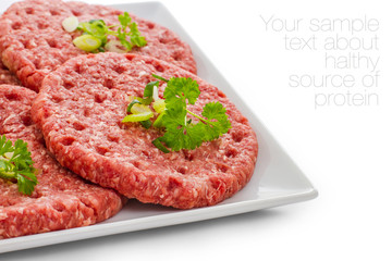 Raw hamburger slices on white plate