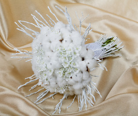 Wedding bouquet of the bride against a golden fabric