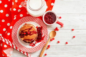 
hearty breakfast, sweet American pancakes with raspberry , cherry or strawberry jam , berries and milk on a wooden background