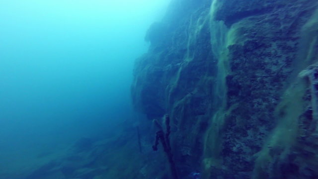 Deep Freediver Exploring a side of a Underwater Cliff into a Quarry