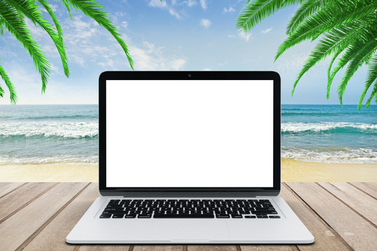Blank white laptop screen on wooden bench at beach background
