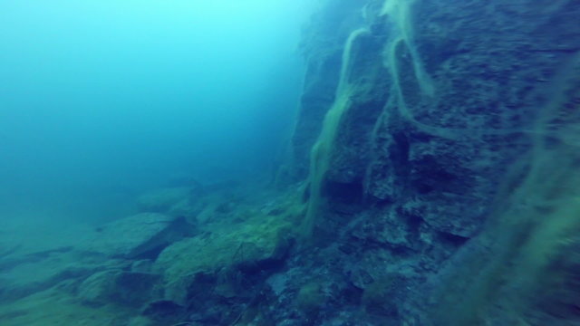 Deep Freediver Exploring a side of a Underwater Cliff into a Quarry