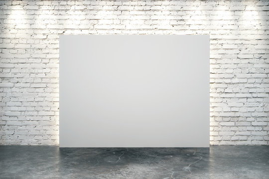 Blank white canvas in the center of white brick wall with concrete floor