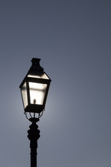 Fototapeta na wymiar Old street lamp on a background of dramatic dark blue skyBacklight. Highlights sun. Space for text