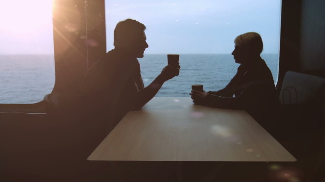 Young Couple in Silhouette Having a Coffee in a Boat in the Morning with a View of the Sunrise and the Ocean