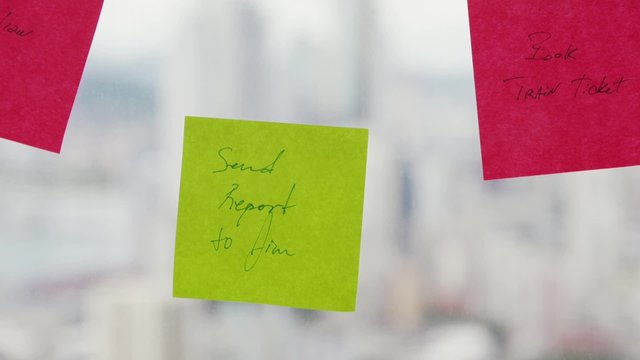 Latin american woman working as secretary in modern office with beautiful sight on the city, sticking adhesive notes with tasks on skyscraper window. Rack focus from the city to her hand. Closeup shot