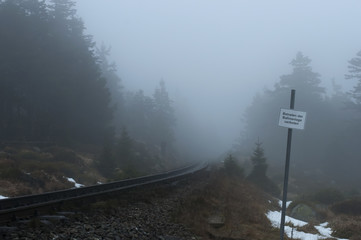 Old railroad with a sign in forest on a foggy winter day in National park Harz, Germany. Horizontal...