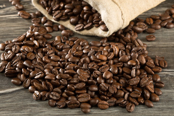 Kaffeebohnen verteilen sich auf einem Tisch um einen Jutesack
