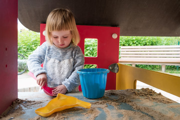 Naklejka premium little girl playing with sand