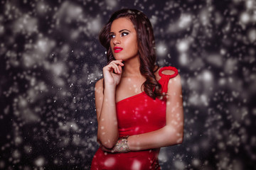 Beautiful girl in red dress on snow.