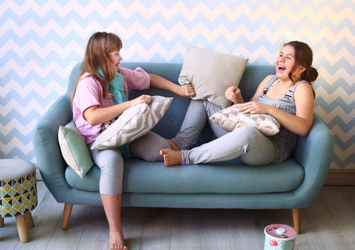  teenager blond sister in pajamas on the sofa