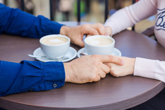 Hands of happy loving couple in a restaurant