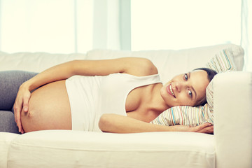 Obraz na płótnie Canvas happy pregnant woman lying on sofa at home