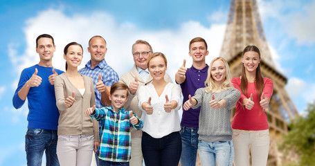 smiling people showing thumbs up over eiffel tower