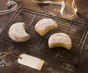 tre biscotti mezzaluna di pasta frolla con zucchero a velo su legno