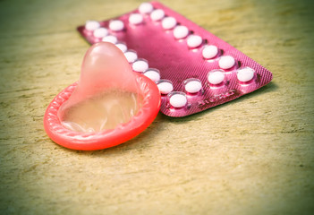 birth control pills and condom on wooden table background.soft and selective focus vintage color tone with filter color effect.