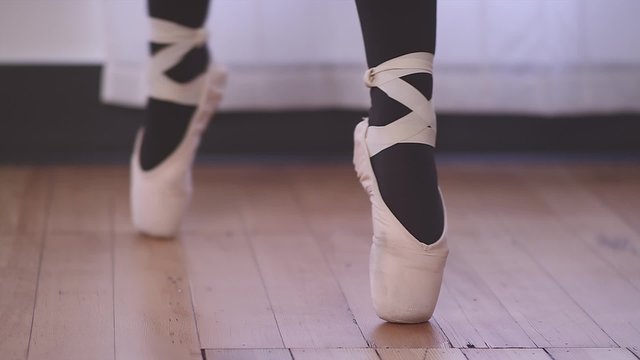 A ballet dancer's shoe goes in and out of focus as she changes positions