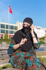Obraz premium Lady in Black Hijab Holding Telephone and talking