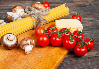 Pasta ingredients - cherry tomatoes, mushrooms,  garlic, broccoli,  cheese on dark background