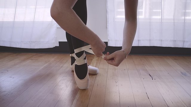 Close up of a ballet dancer tying up her ballet shoes