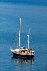 Fototapeta premium Boat whith flagpole on the water surface against the backdrop of the hill