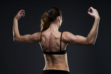 Fototapeta na wymiar Attractive fitness woman on gray background in studio. Muscular back close-up