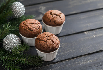 Chocolate muffins,  Christmas tree and Christmas decorations on dark wooden surface