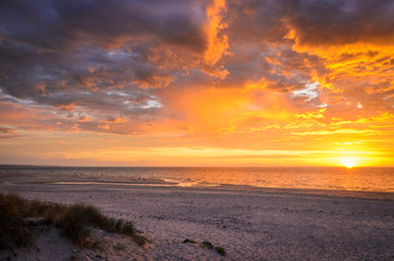 Fototapeta premium Dramatic sunset at the beach through dunes