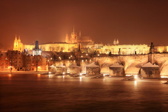 Night snovy christmas Prague gothic Castle and St. Nicholas' Cathedral with Charles Bridge, Czech republic