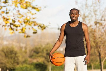 Afroamerican man street basket player holding a basketball outdo