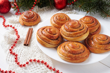 Obraz na płótnie Canvas Cinnamon bun rolls homemade christmas sweet dessert on white vintage table with new year decorations. Traditional swedish kanelbullar baked pastry