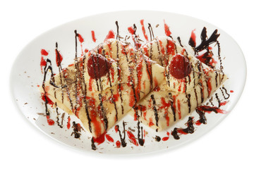 Two folded pancakes with sweet filling served on a white plate with parfait cream, strawberries, hazelnuts and chocolate. Isolated on white.