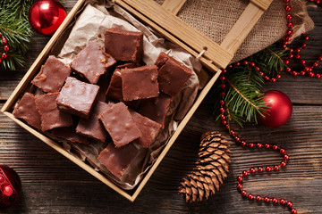 Christmas fudge traditional homemade chocolate sweet dessert food in wooden box on vintage table background. Top view. Delicious unhealthy snack