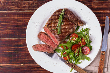 Ribeye steak with arugula and tomatoes.