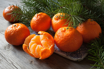 Tangerines on a wooden table with branches of fir