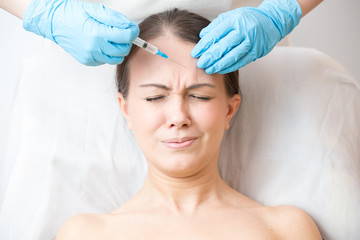 Young woman wincing from pain during cosmetic injection