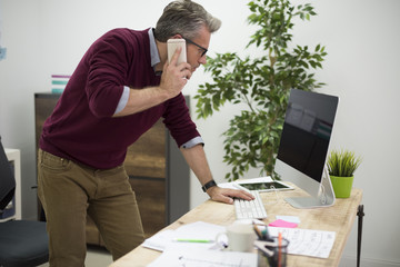 Working man bending over the desk - obrazy, fototapety, plakaty