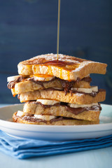 pouring caramel over french toasts with banana chocolate saucel