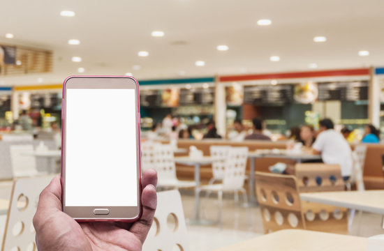Hand with smartphone on blurred in food court background